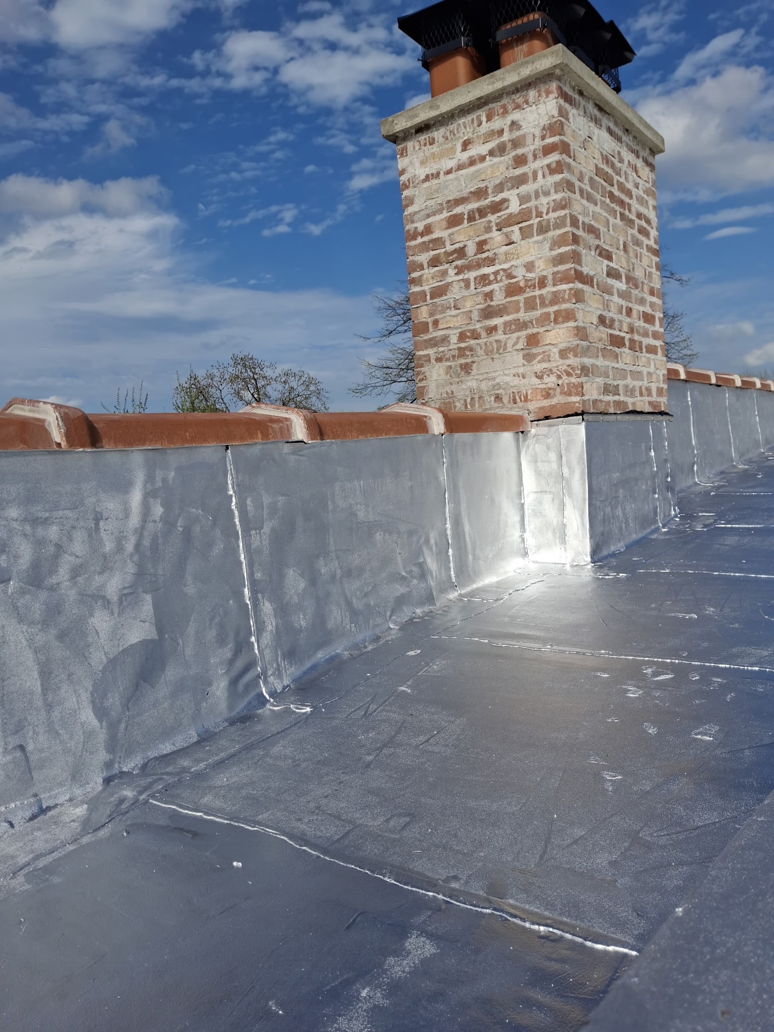 Completed brick chimney and silver-coated flat roof detail